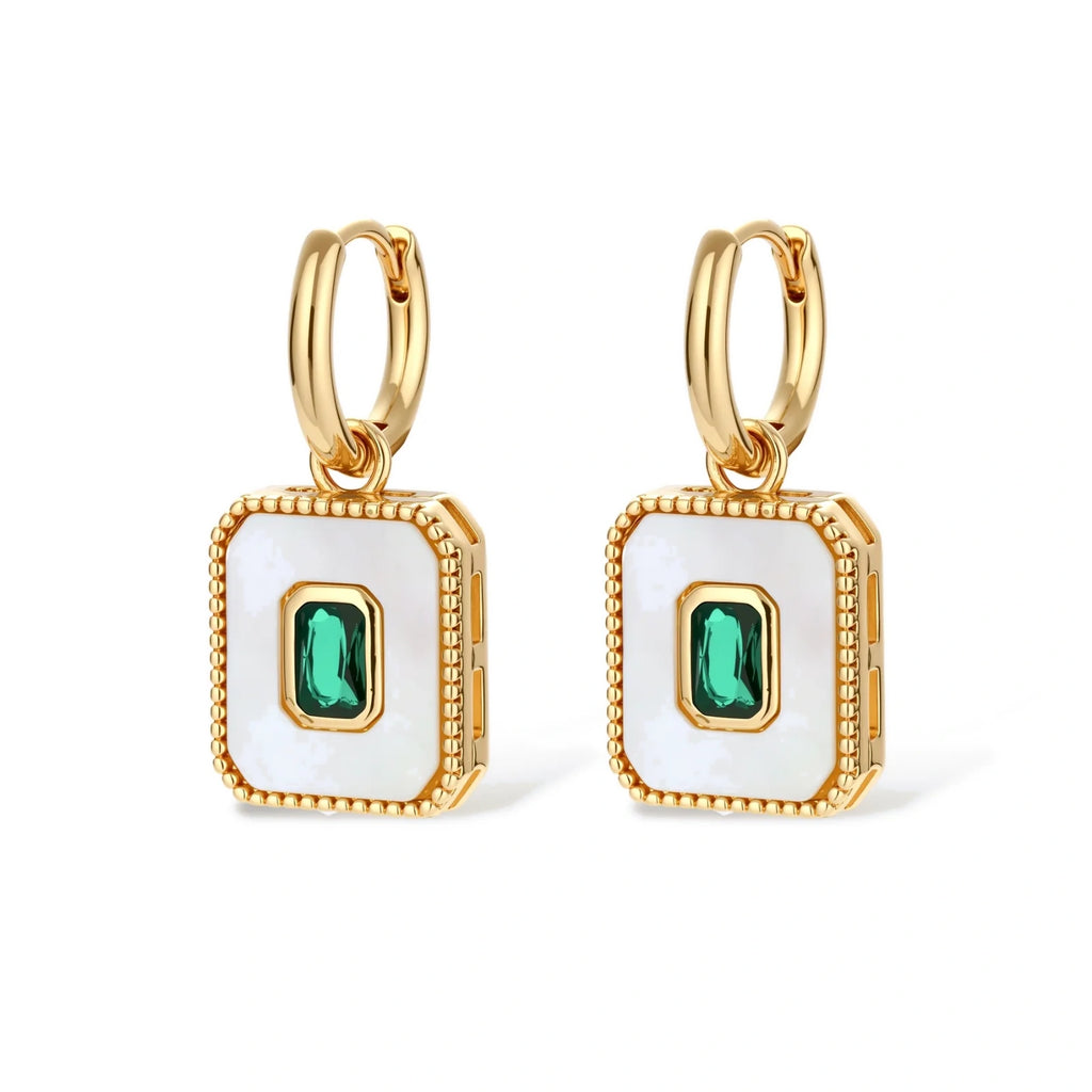 Gold-plated jewelry set with white enamel square pendants and emerald CZ stones on cream background.