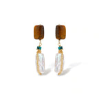 Gold-plated drop earrings with amber stones, teal beads, and wire-wrapped baroque pearls on cream background.