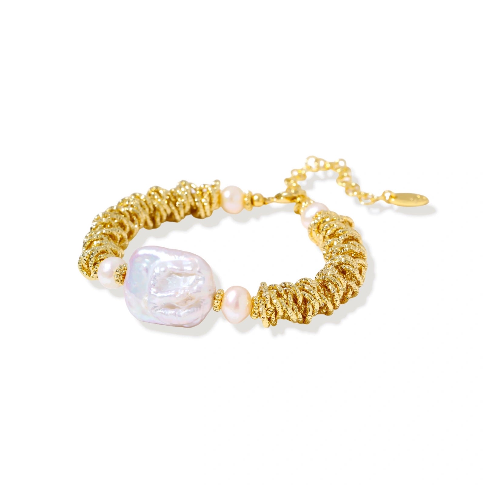 18k gold-plated bracelet with textured wave segments, baroque pearl centerpiece, and round freshwater pearls on cream background