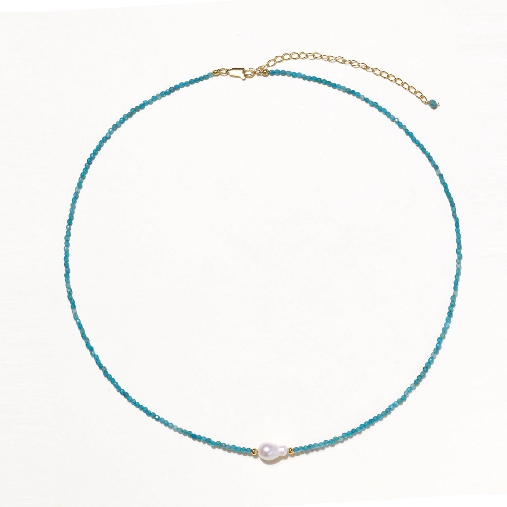 Delicate gold vermeil necklace with teal apatite beads and freshwater pearl on white background.