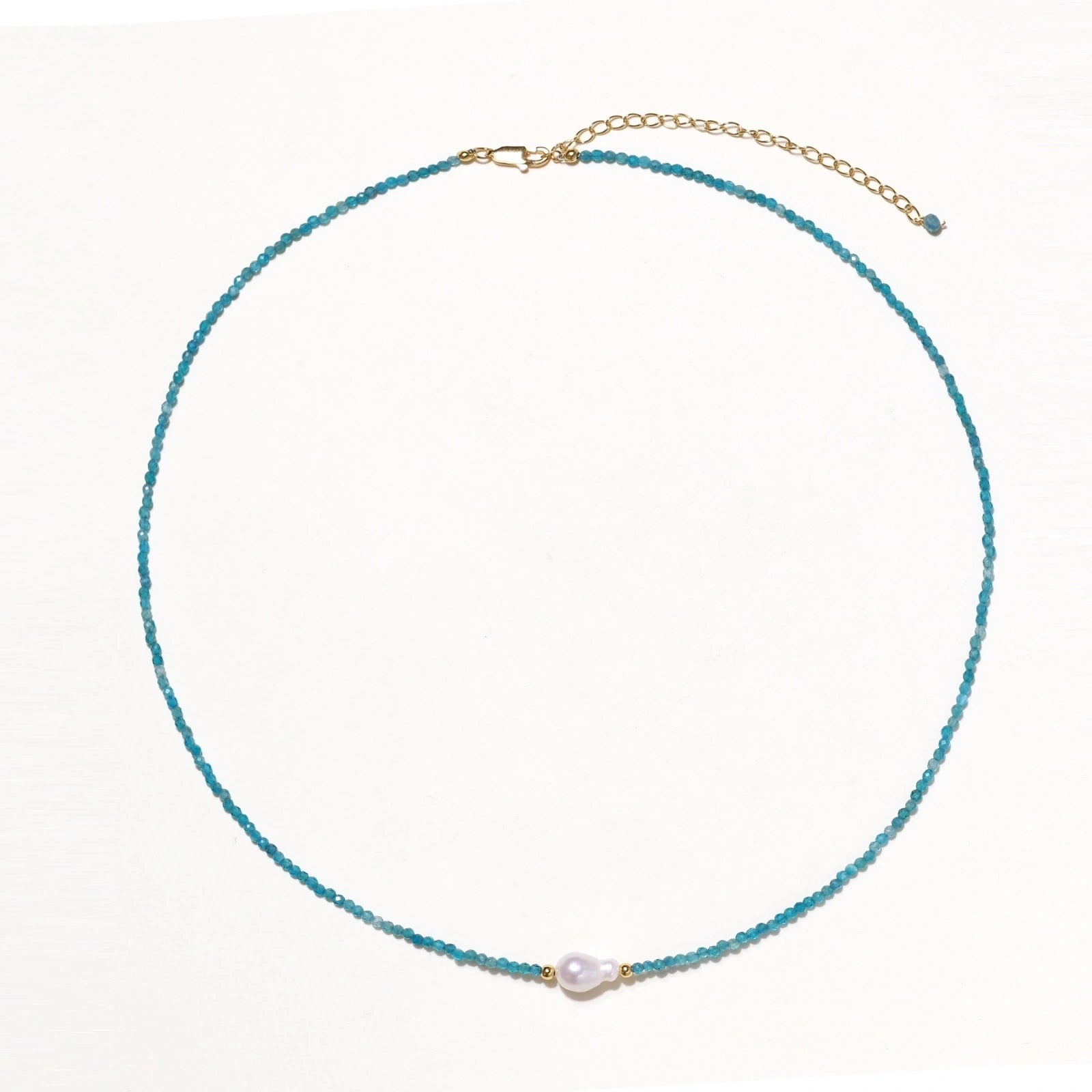Delicate gold vermeil necklace with teal apatite beads and freshwater pearl on white background.