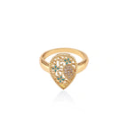 Teardrop-shaped gold-plated ring with turquoise enamel flowers and crystal pavé detail on cream background