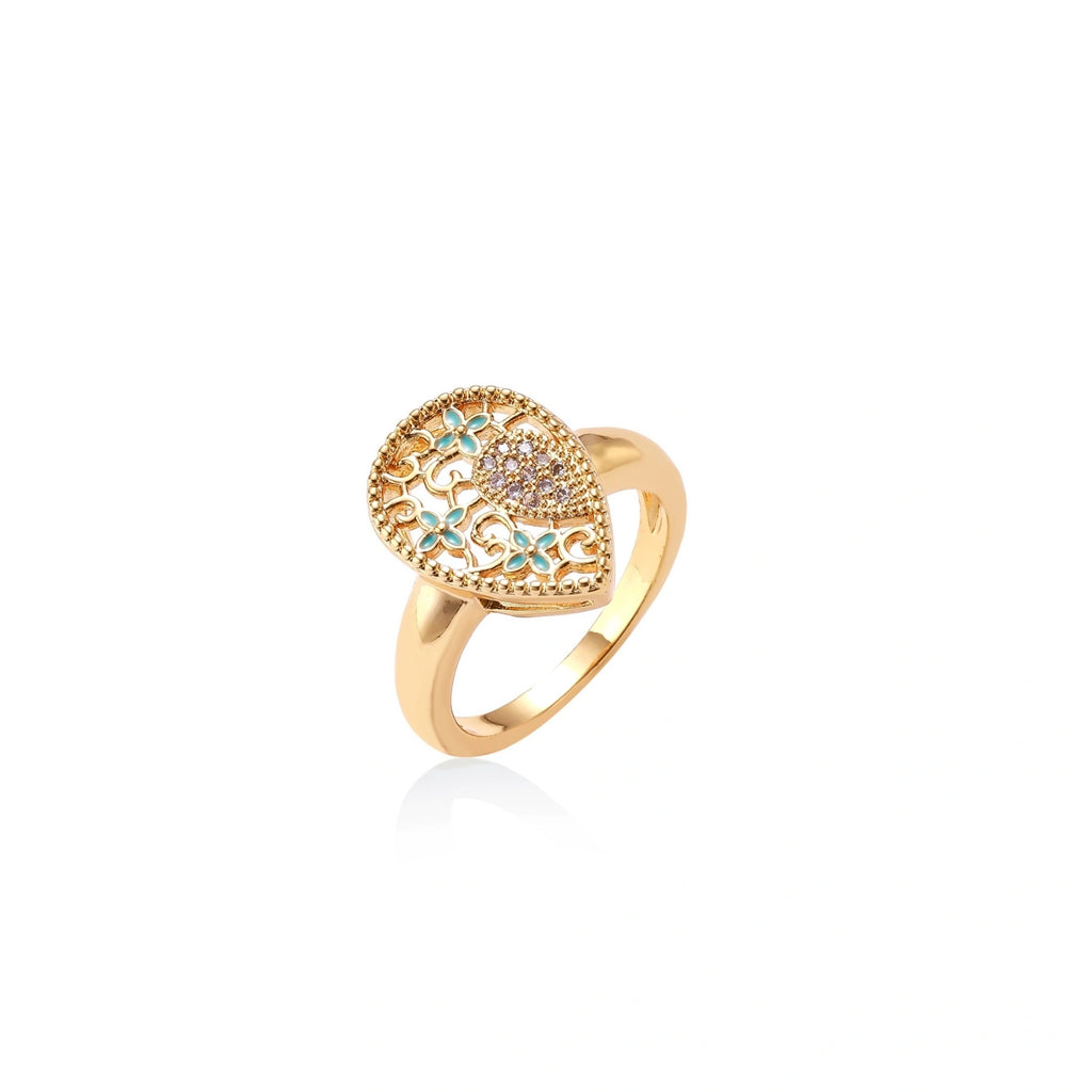 Teardrop-shaped gold-plated ring with turquoise enamel flowers and crystal pavé detail on cream background