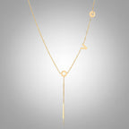 Gold Y-shaped necklace with L-O-V-E letter charms and vertical bar pendant on delicate chain against cream background