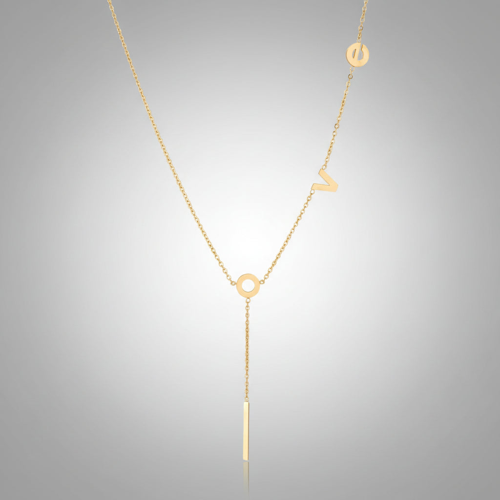 Gold Y-shaped necklace with L-O-V-E letter charms and vertical bar pendant on delicate chain against cream background