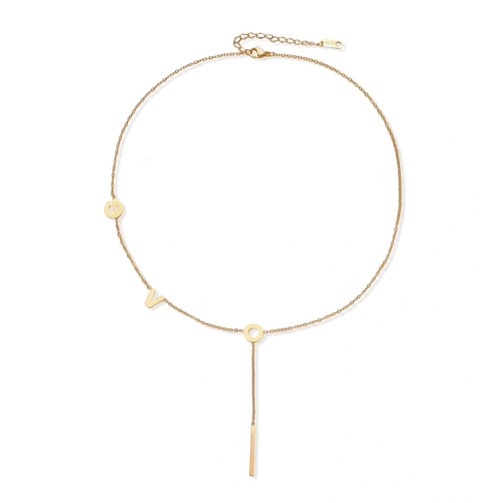 Gold Y-shaped necklace with L-O-V-E letter charms and vertical bar pendant on delicate chain against cream background