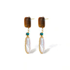Gold-plated drop earrings with amber stones, teal beads, and wire-wrapped baroque pearls on cream background.